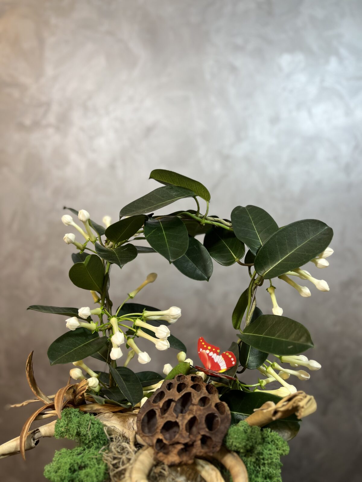 Derin Flowers’ın 'Kokulu Madagaskar Yasemini' aranjmanının yakın plan görüntüsü; minik beyaz çiçekler, dekoratif uğur böceği, kuru lotus kapsülü ve doğal detaylarla süslenmiş zarif bitki tasarımı.